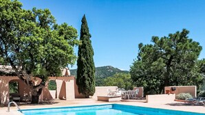 Ein Pool mit klarem, blauem Wasser, umgeben von Bäumen und einem Berg im Hintergrund.