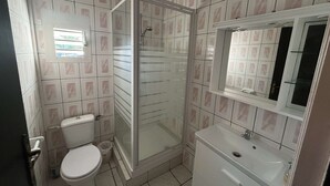 A bathroom with a toilet, a shower enclosure, and a sink. - Studio Zoizo White (Saint-Pierre)