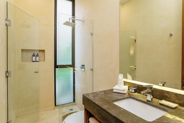 A modern bathroom with a glass shower enclosure, a marble sink, and a large mirror.