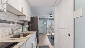 A modern kitchen with white cabinets, a marble countertop, and a built-in oven.