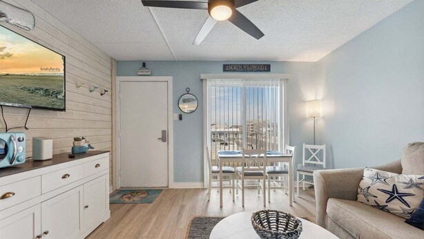 A room with a dining area, a sofa, a ceiling fan, a TV, and a sign reading 'NORTH WILDFORD.'