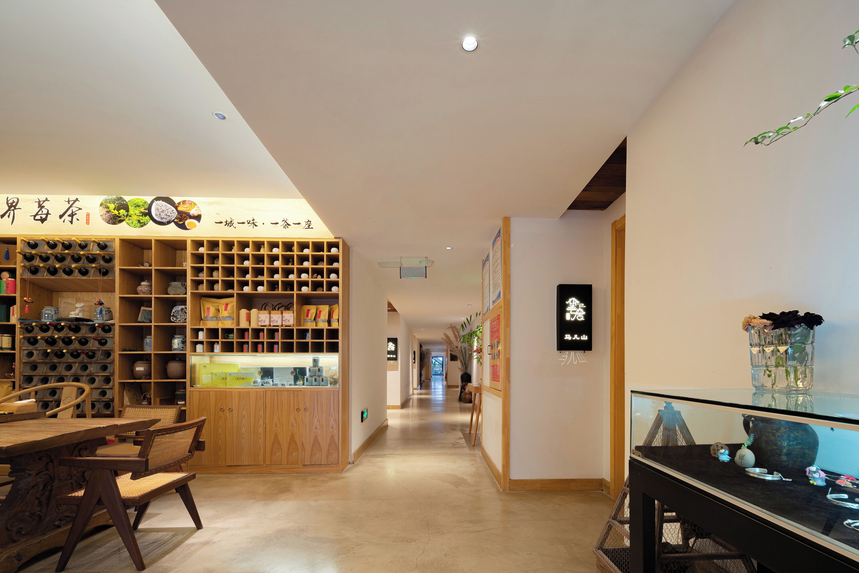 A hotel lobby with a long corridor, wooden furniture, and shelves with various items.