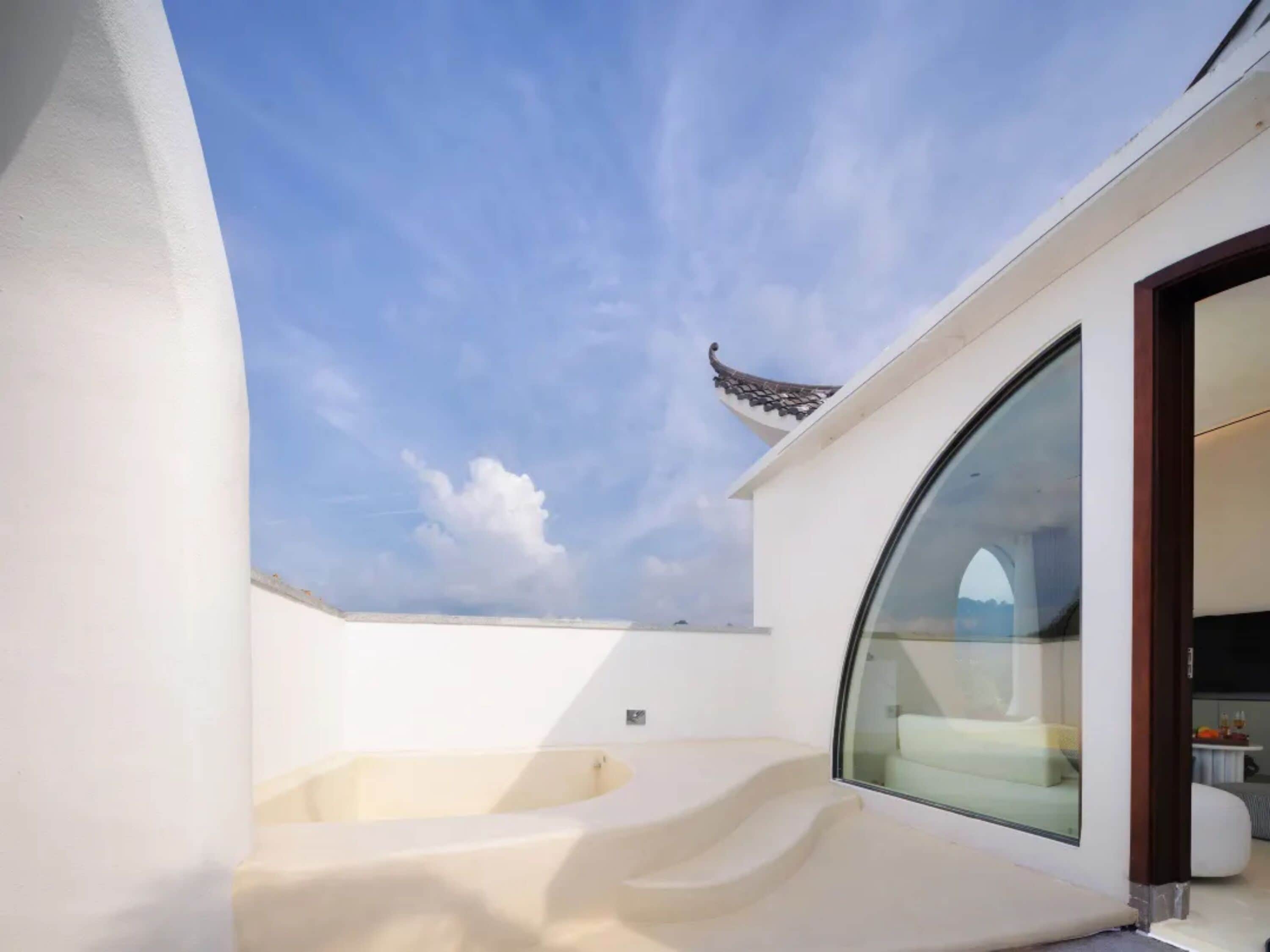 Eine moderne Dachterrasse mit einem gewölbten Glasfenster, einem kleinen Pool und traditioneller Dachkonstruktion.