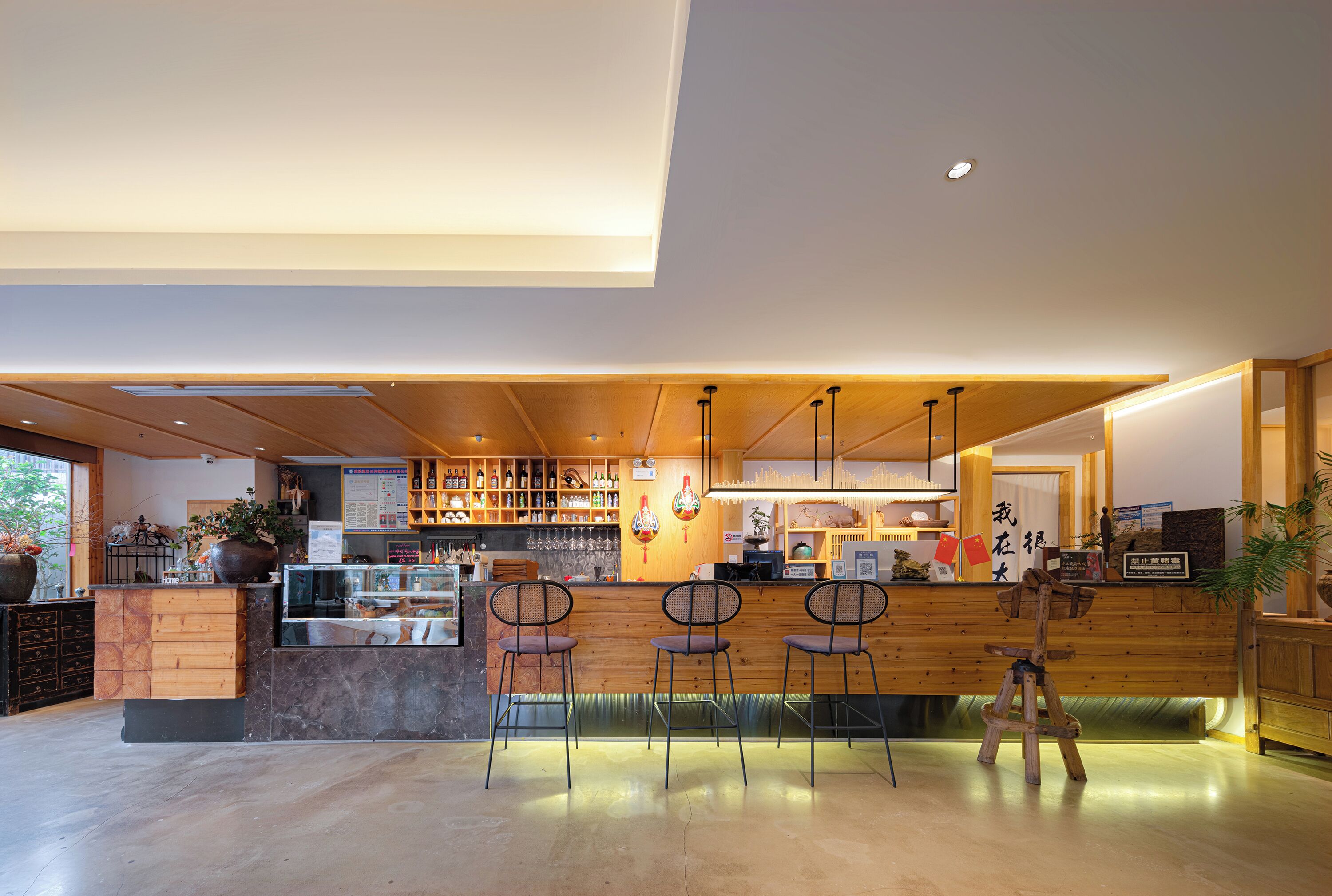 A modern bar area with wooden counters, bar stools, and a variety of bottles and glasses.