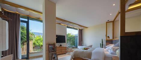 A modern hotel room with a large bed, a sofa, a desk, and a TV.