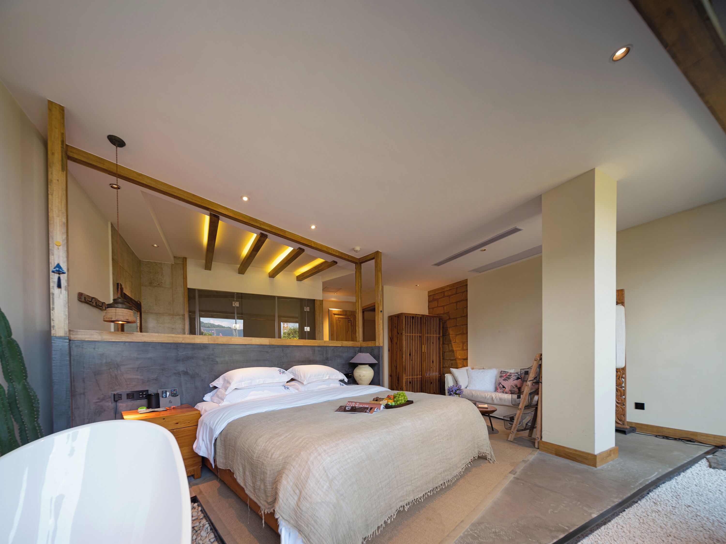 Un dormitorio moderno con una cama grande, cabecera de madera, un espejo amplio y vistas al exterior.