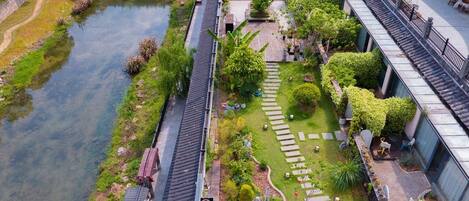 Un bâtiment de style traditionnel, avec un jardin, une rivière et un pont en arrière-plan.