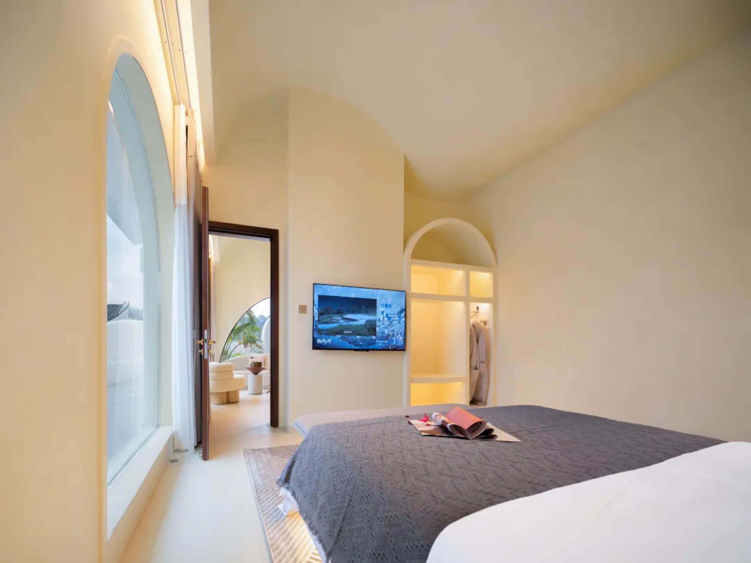 Une chambre à coucher avec un lit, une télévision et une vue sur un balcon.
