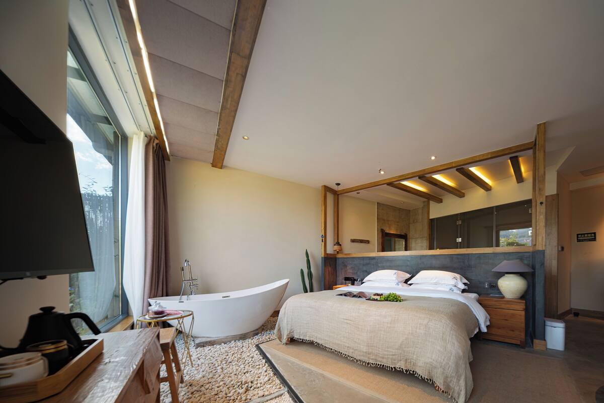 Ein modernes Schlafzimmer mit einem großen Bett, einer Badewanne und einem Fernseher.