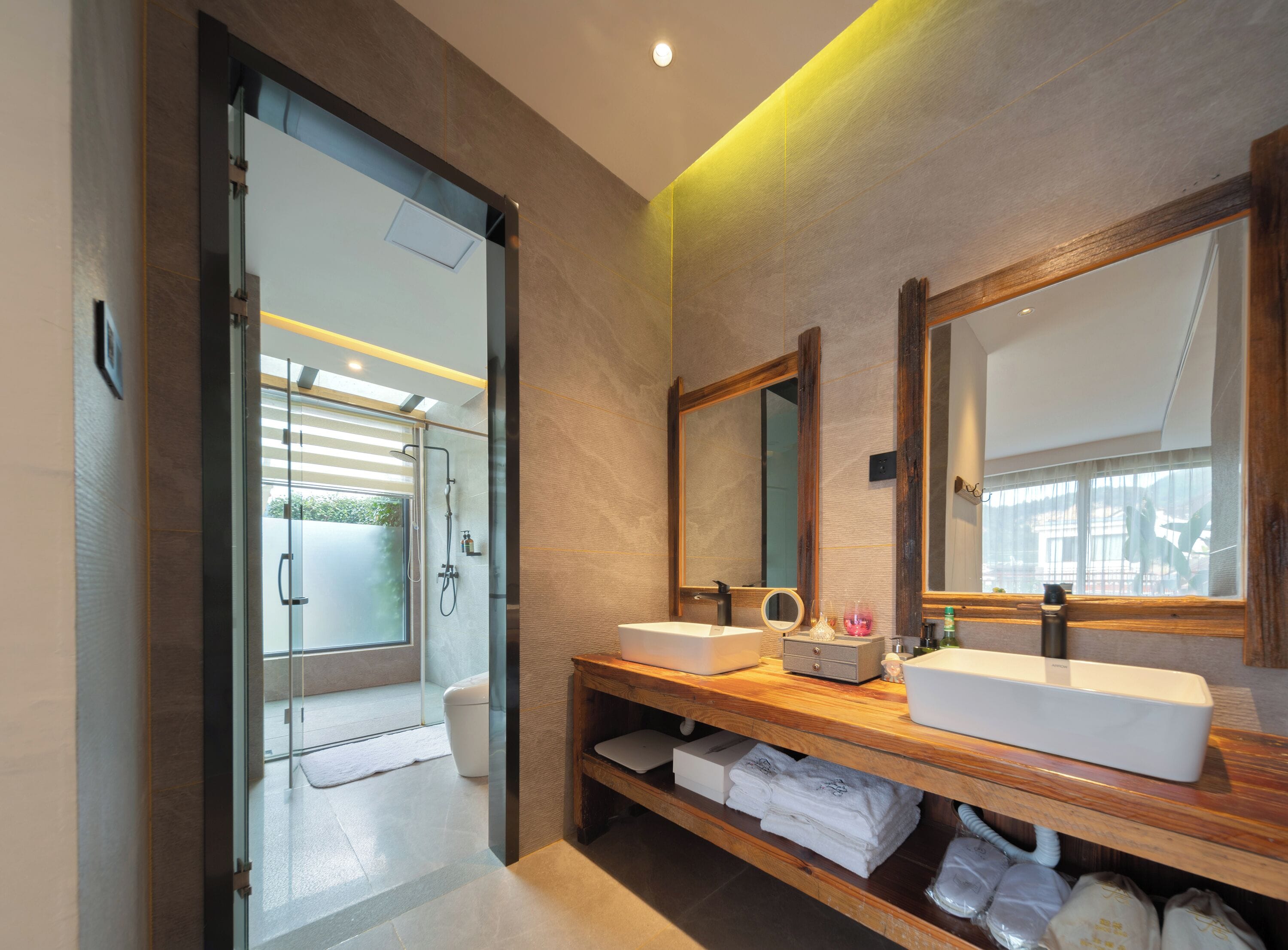 A modern bathroom with a glass shower enclosure, dual sinks, and a vanity with towels.