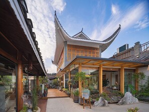 A traditional building with a sloped roof and wooden structure, surrounded by potted plants and a wooden deck. - Wang Yun Residence Boutique Homestay (Zhangjiajie)