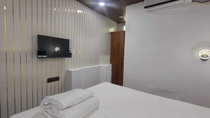 A hotel room with a bed, a flat-screen TV mounted on the wall, a wooden wardrobe, and a radiator. - Hotel M Hyatt (Hyderabad)