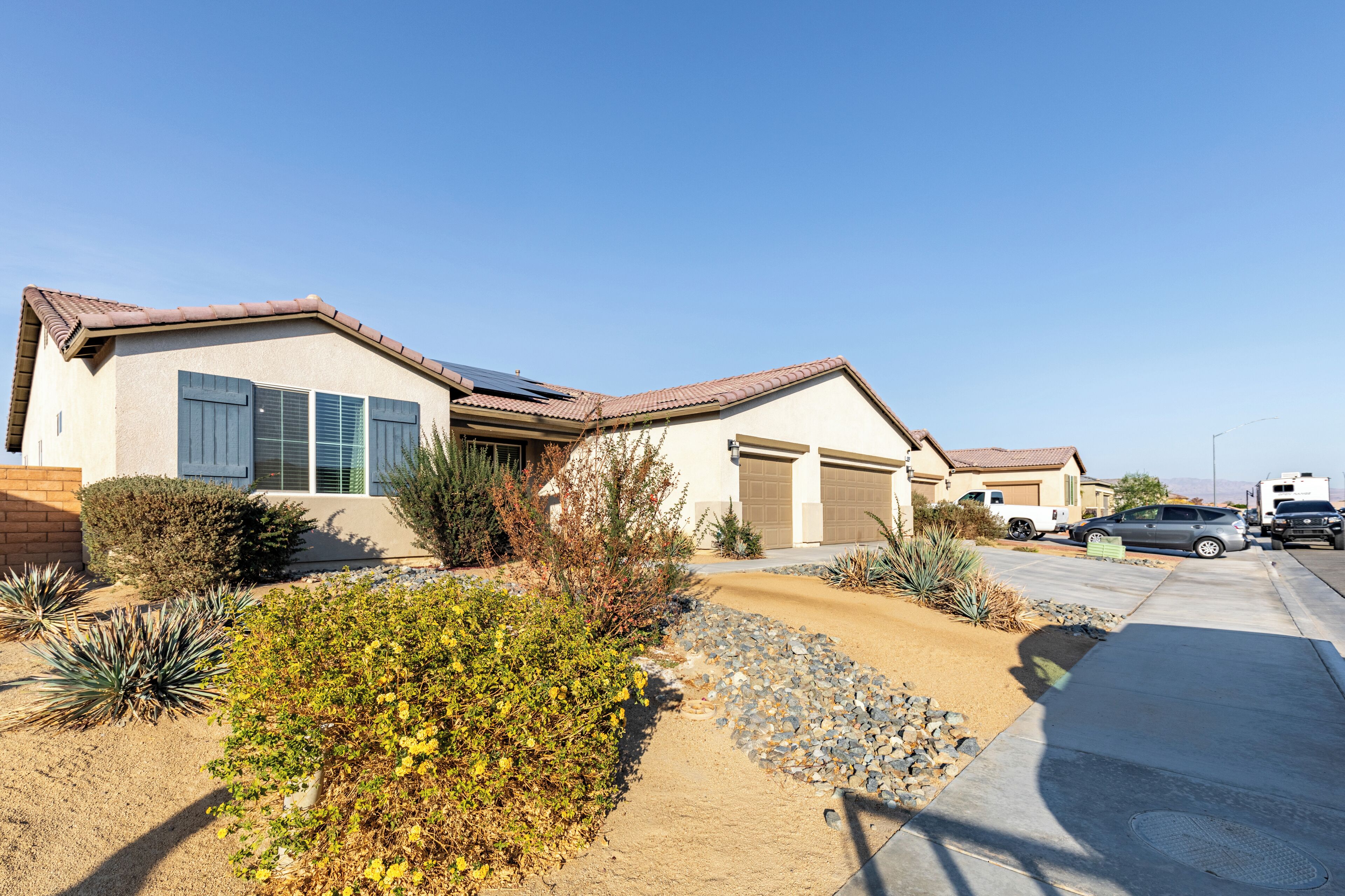 A residential area with two houses, a driveway, and parked vehicles.