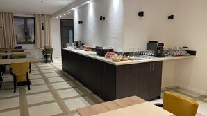 Una cocina moderna con armarios oscuros, una isla central y un comedor con sillas amarillas y una mesa de madera.