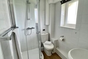 Ein Badezimmer mit Duschkabine, Toilette und Badewanne.