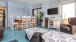 Um espaço de estar compacto com área de jantar, cozinha compacta e uma janela grande.