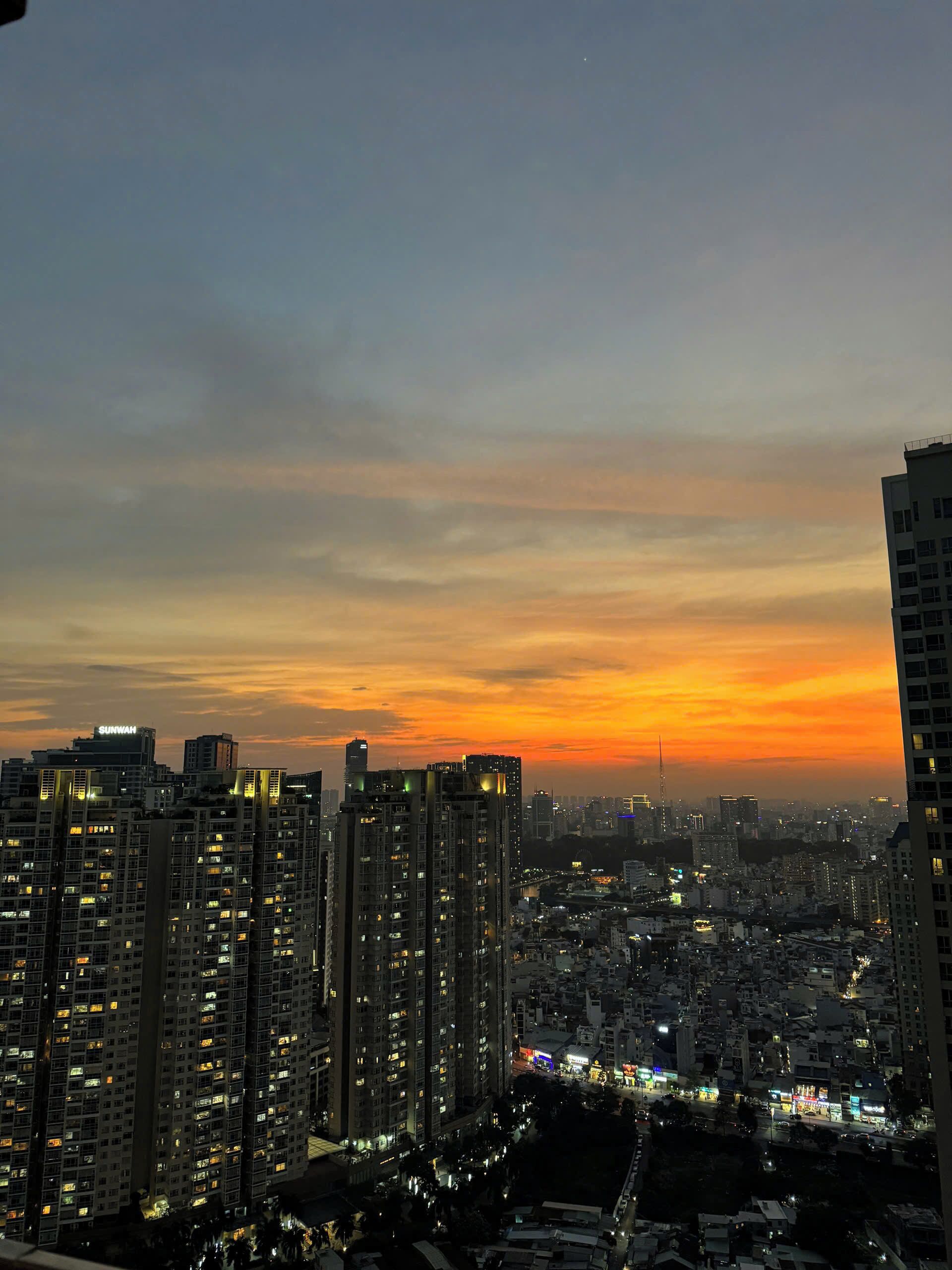 A cityscape at dusk with high-rise buildings and a sunset.