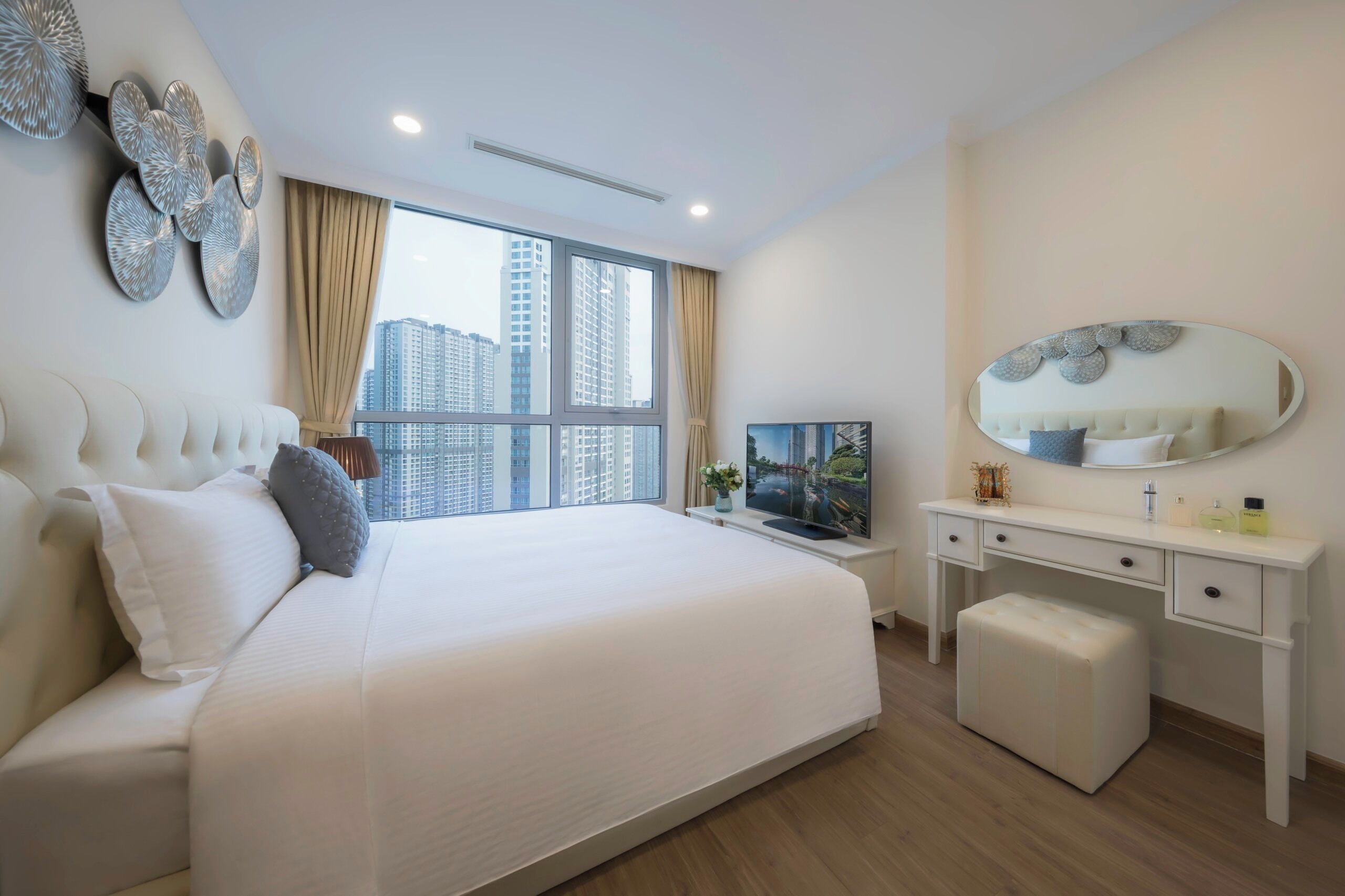 Una habitación de hotel moderna con una cama grande, un escritorio, un televisor y vistas a edificios altos.