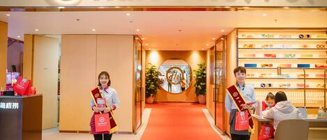 Entrada de un hotel con alfombra roja, una recepción y exhibición de servicios.