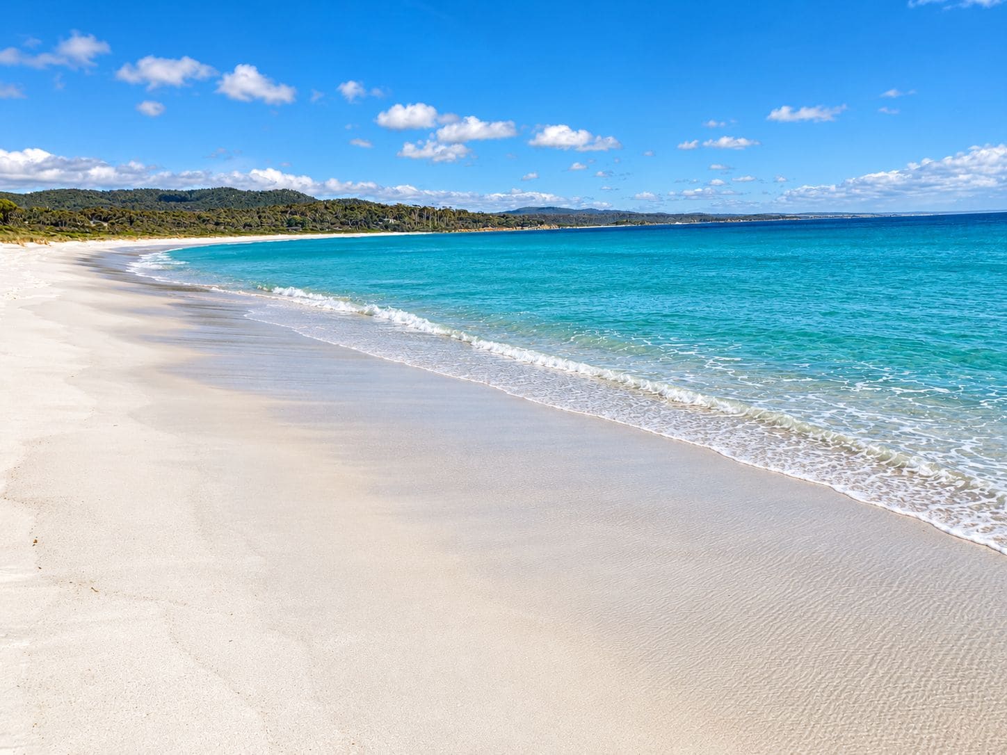 A beach with clear turquoise waters and a sandy shore.