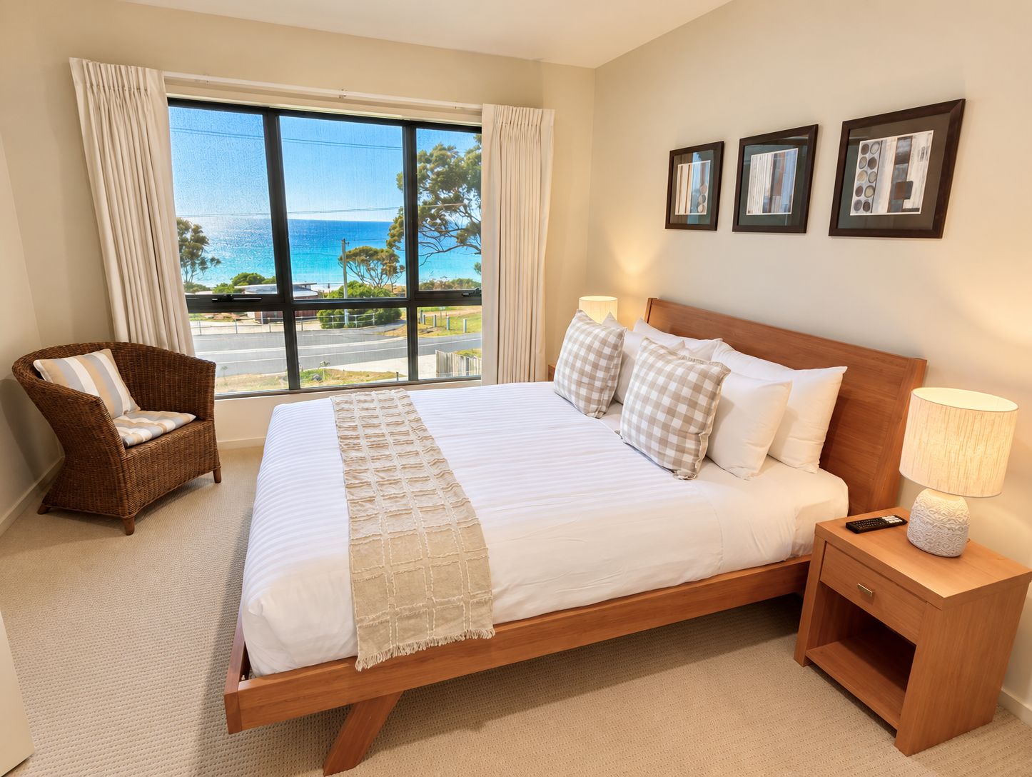 A hotel room with a large bed, a chair, a nightstand, and a view of the ocean.