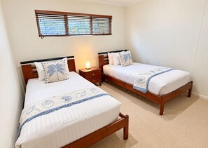 A bedroom with two single beds, a nightstand, a bedside lamp, and a window with blinds. - Lichen Villa Bay of Fires  - Binalong Bay beach is at your doorstep (Binalong Bay)