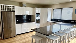 Una cocina moderna con una isla central, electrodomésticos de acero inoxidable y armarios blancos.