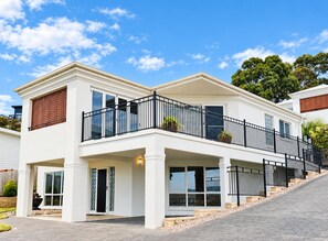 A two-story residential building with a balcony, large windows, and a stone-paved driveway. - Lichen Villa Bay of Fires  - Binalong Bay beach is at your doorstep (Binalong Bay)