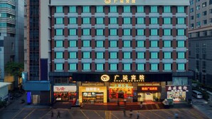 Et hotel med en moderne facade, flere balkoner og en markant indgang med oplyst skilte.