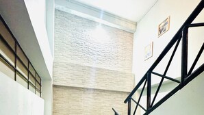 Una scala con ringhiera in metallo nero e una parete chiara con motivo strutturato.
