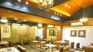 A restaurant with wooden ceiling, marble tables, and cushioned chairs. - Onyx Garden Boutique Hotel (Guwahati)