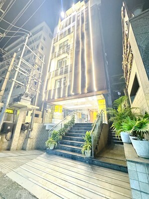 A hotel entrance with a staircase, potted plants, and a sign indicating the hotel name. - Onyx Garden Boutique Hotel (Guwahati)