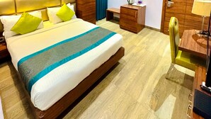 A modern hotel room with a large bed, a ceiling fan, an air conditioning unit, a bedside table with a lamp, and a wooden wardrobe. - Onyx Garden Boutique Hotel (Guwahati)