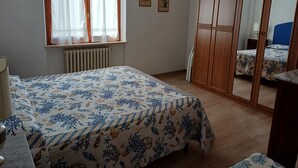 A bedroom with a bed, a wardrobe, a radiator, and a window with curtains. - Apartment 1st row sea with beautiful terrace (Grottammare)