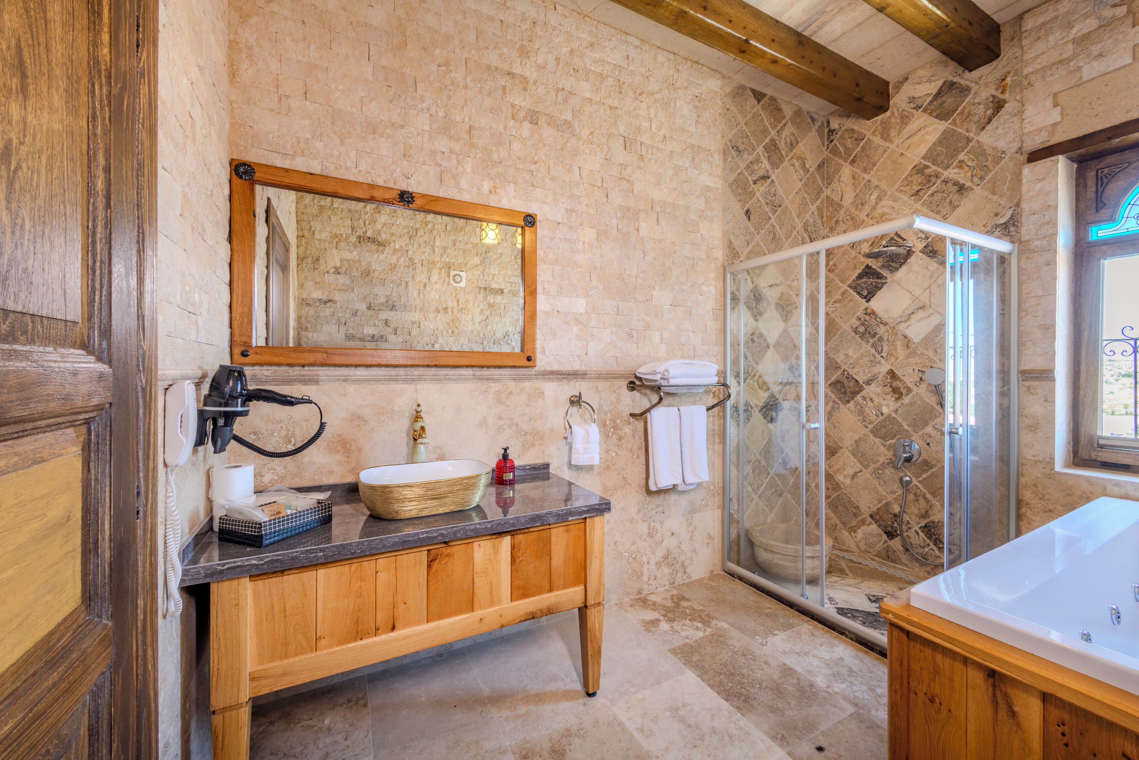 A bathroom with a wooden vanity, a large mirror, a shower with a glass door, and a bathtub.