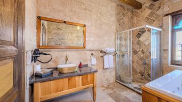 A bathroom with a wooden vanity, a large mirror, a shower with a glass door, and a bathtub.