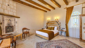 A bedroom with a bed, a chair, a table, a rug, and a decorative wall.