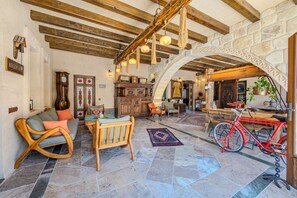A spacious interior with a stone wall, wooden beams, a reception area, a dining area, and a bicycle. - Karis Cave Cappadocia (Ürgüp)