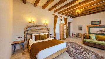 Un dormitorio con una cama de madera, un sofá verde, un tapiz estampado y un techo de madera con vigas a la vista.