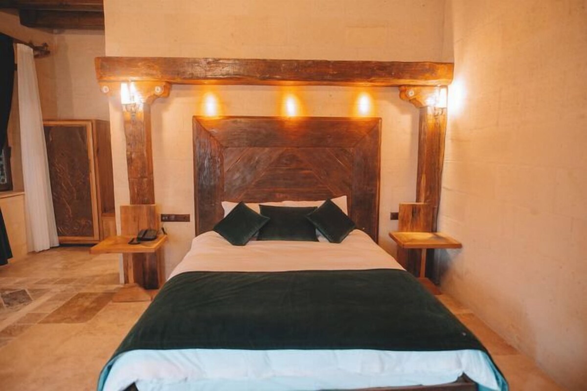 A bed with a wooden headboard, two bedside tables, and a nightstand with a lamp.