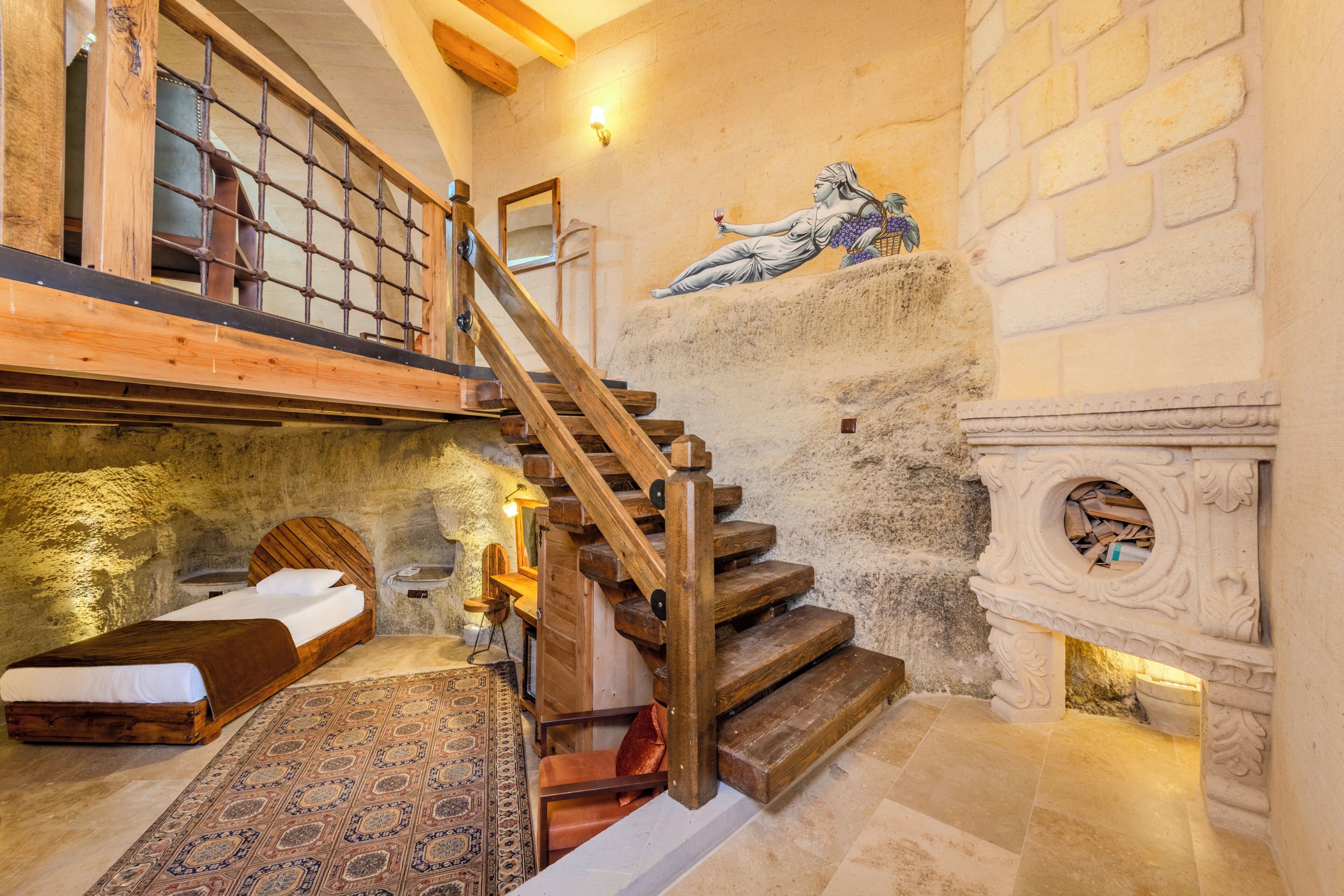 A rustic room with a wooden staircase, a stone wall, and a bed with a patterned rug.