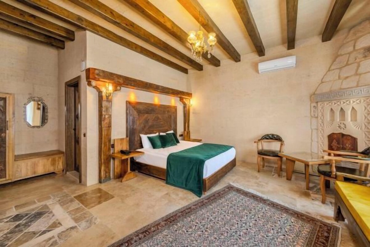 A bedroom with a wooden bed, a nightstand, a chair, and a table.