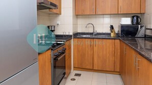 Een moderne keuken met houten kastjes, een roestvrijstalen fornuis, een magnetron en een spoelbak.