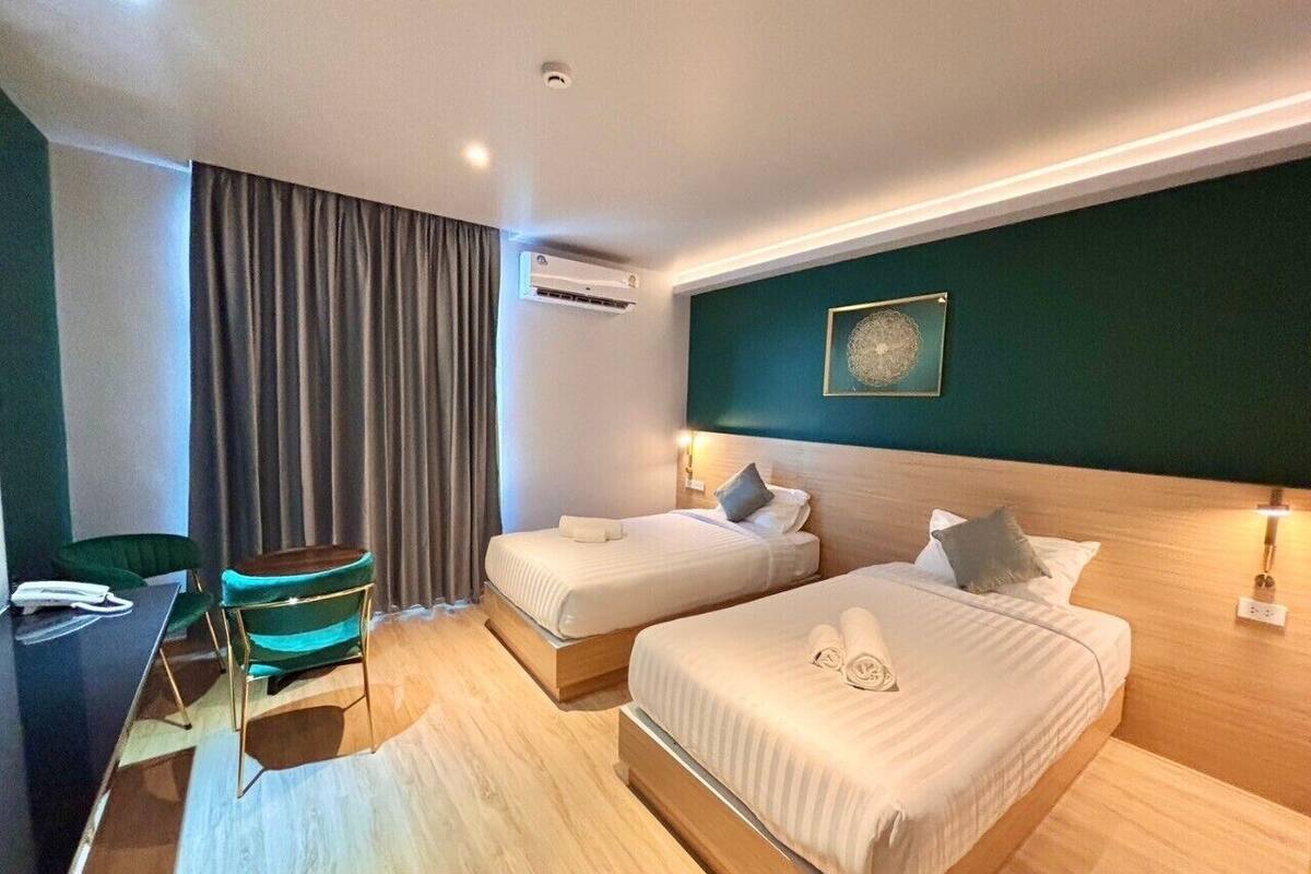 A hotel room with two beds, a desk, and a chair.