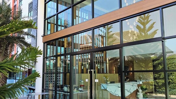 A modern hotel lobby with large glass windows, a reception desk, and a patterned floor. - The Essence HOTEL Chanthaburi (Chanthaburi)