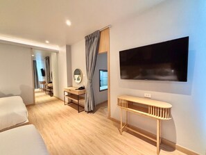 A modern hotel room with a large bed, a desk with a computer, a TV mounted on the wall, and a small table. - The Essence HOTEL Chanthaburi (Chanthaburi)