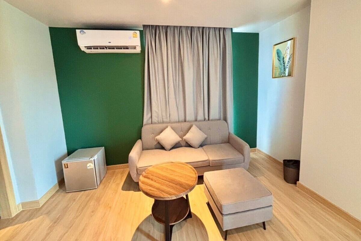 A modern living room with a grey sofa, a wooden coffee table, and a small air conditioning unit.