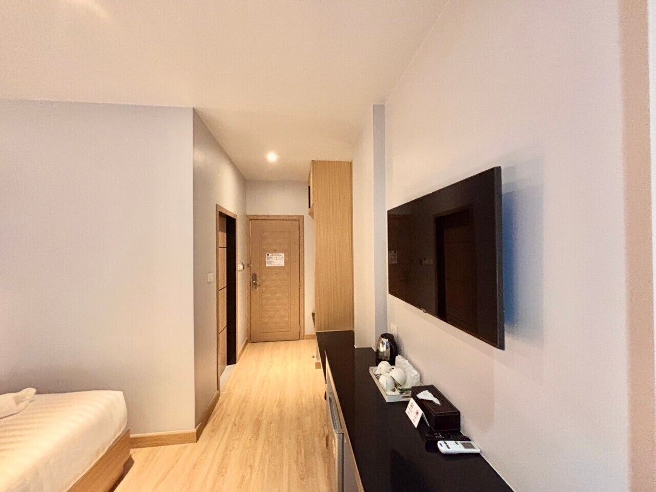 Una camera d'albergo con un letto, una scrivania con un computer, una televisione e una porta che dà su un'altra stanza.