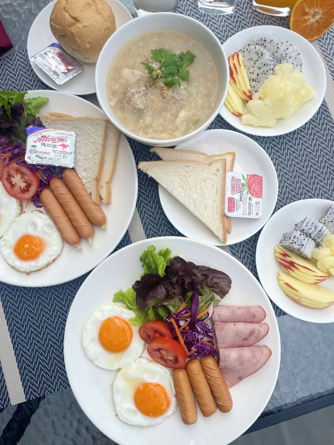 Pöydällä on useita erilaisia ruokalajeja sisältävä ateria, kuten keittoa, makkaroita, kananmunia ja kasviksia.