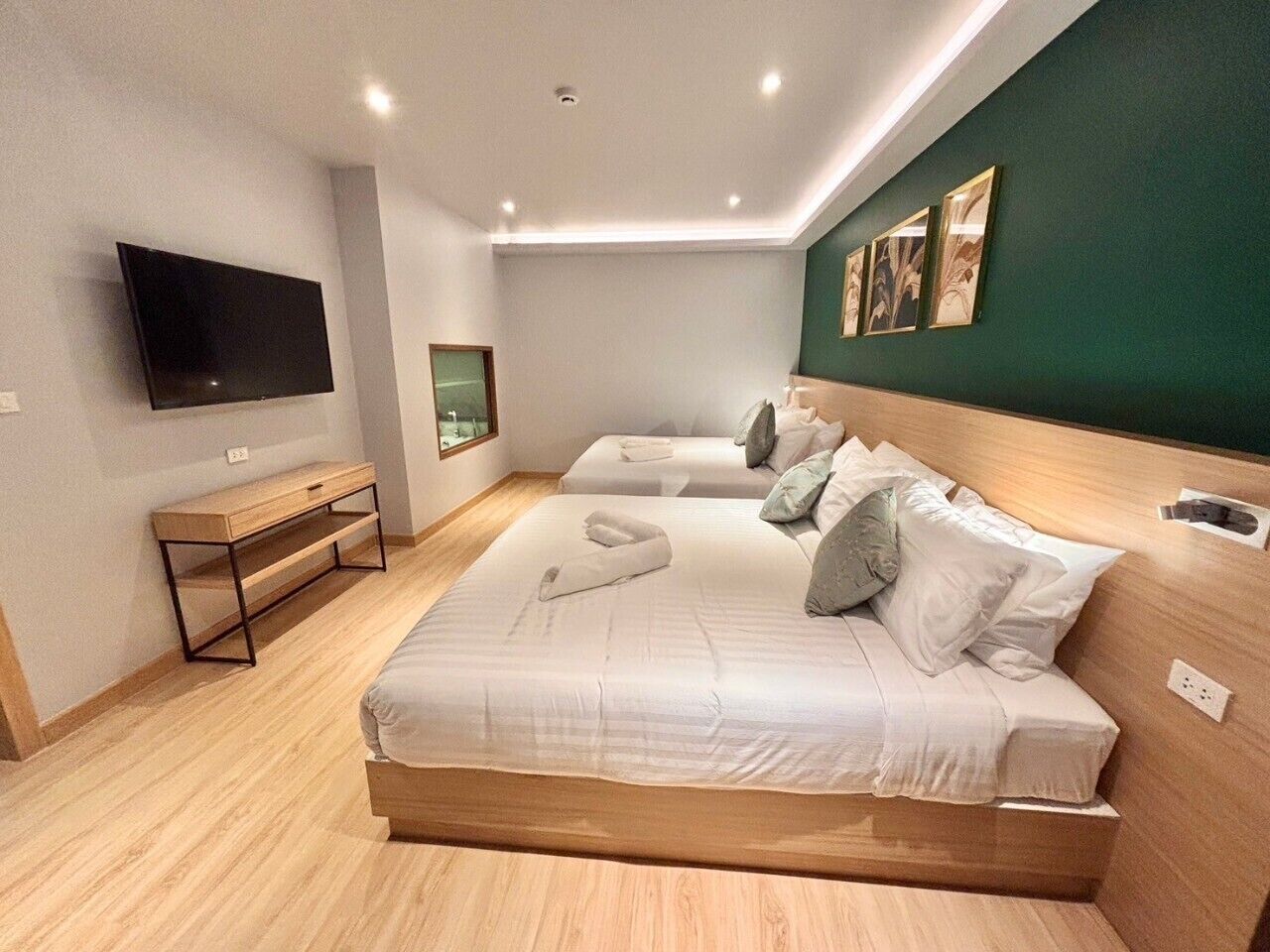 Une chambre d’hôtel avec deux lits, un téléviseur à écran plat, un banc en bois et des œuvres d’art accrochées au mur.